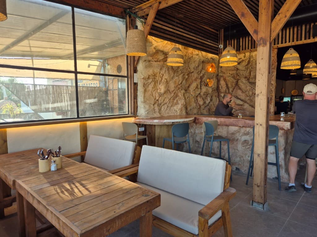 Seating corner with wooden tables, windows and a stone wall