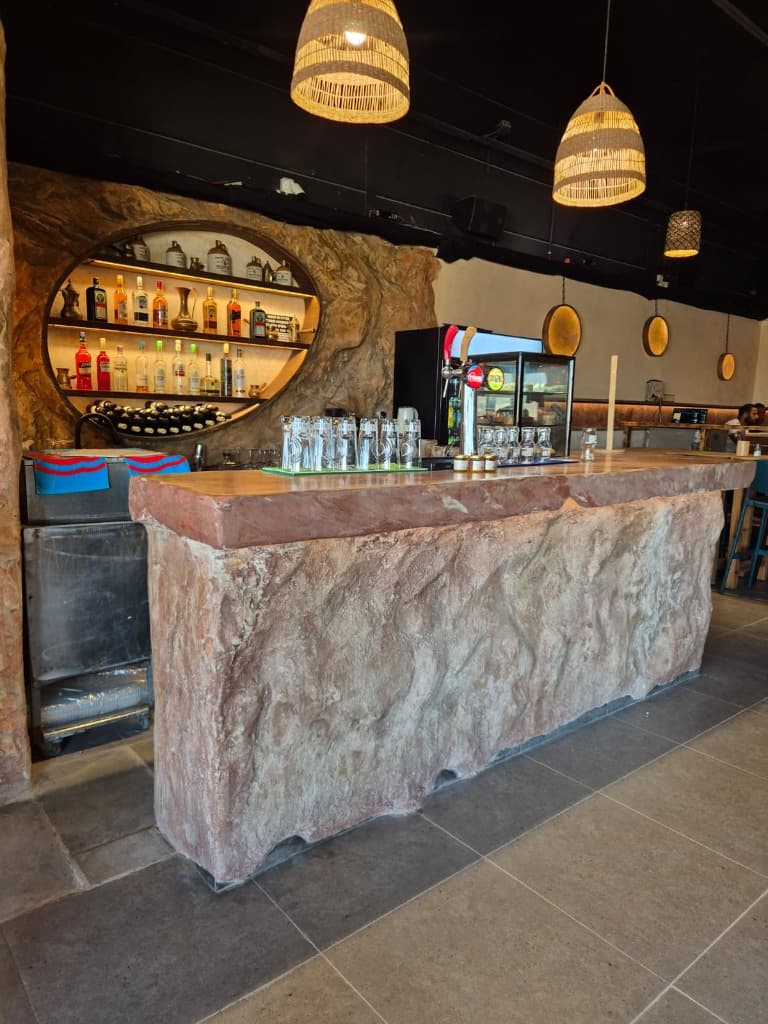 Natural stone bar counter with drink shelves and straw lighting